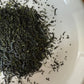 Close-up of dried Hoshino Shizuku 2026 sencha leaves on a white plate, showing the fine needle-like leaf shape